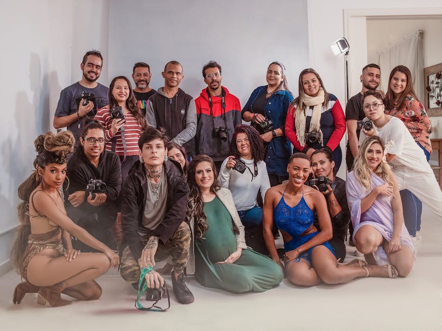 A diverse group of photographers and models posing in a bright indoor studio setting, exuding joy and collaboration.