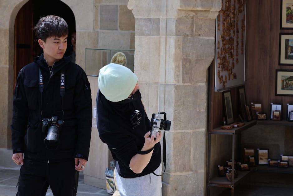 Two photographers interact outside an art gallery, observing and capturing details.